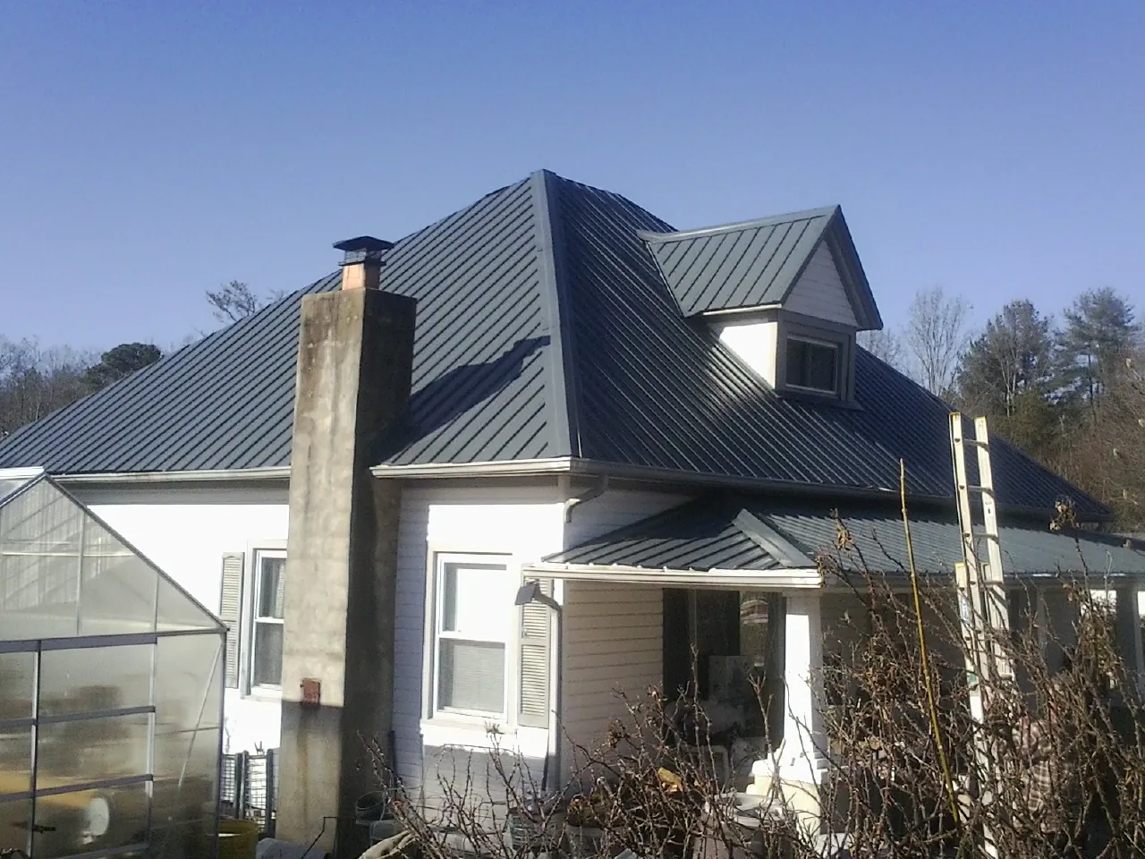 Dark blue standing seam metal roof on a white farmhouse with dormer — Slate & Tile Roof Repair by Roofing Brothers in Rockton