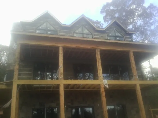 Dormers and porch framing on a large log home under construction — Roof Coating work by our crew in Rockton