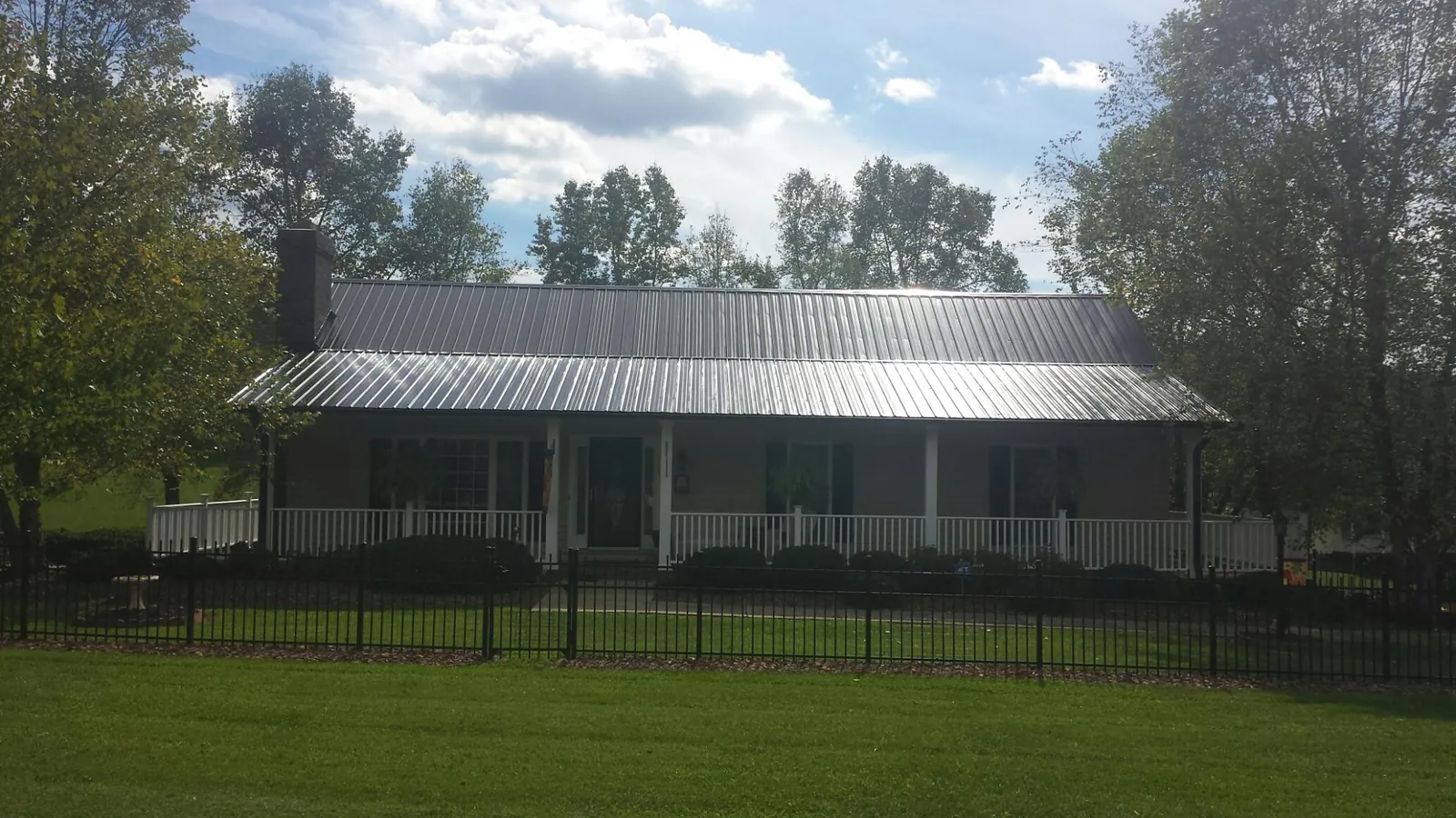 Gray metal roof on a brick ranch with a full width front porch — Gutter Guard Installation work by our crew in Rockton