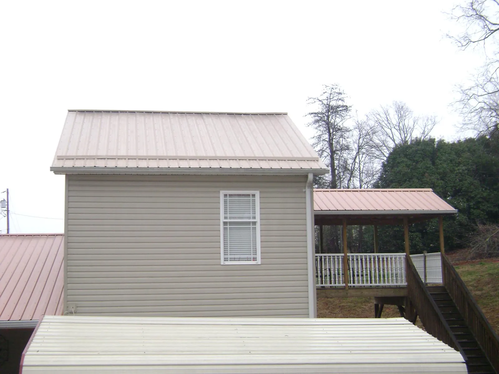 Tan metal roofs on a two story addition and attached porch, from a Roof Replacement job in Rockton