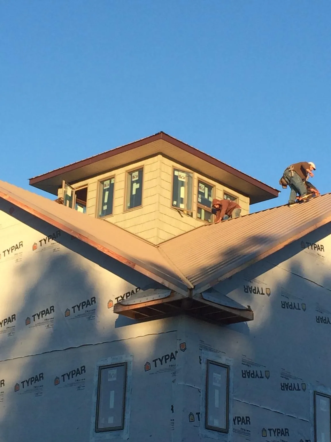 Roofers working around a rooftop cupola on a new metal roof at sunset — Roof Waterproofing in Rockton by Roofing Brothers